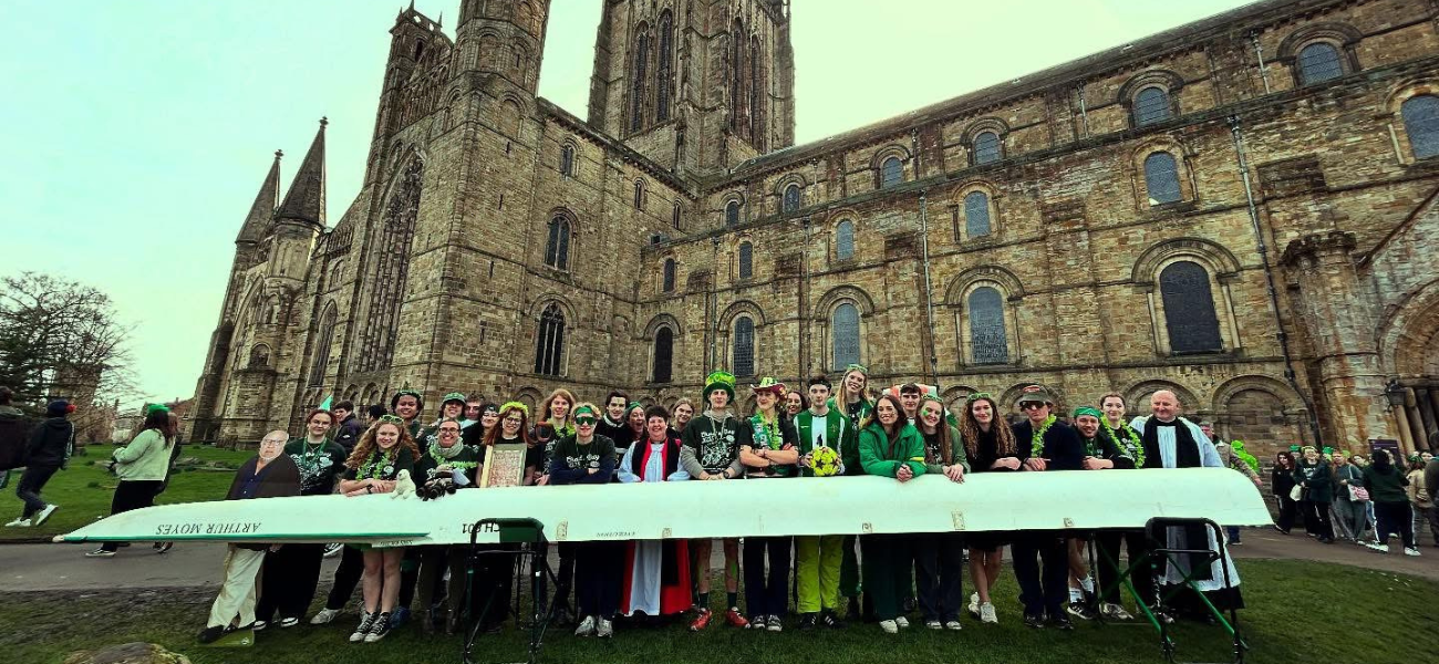 Students stand with an eight boat on Chad's day